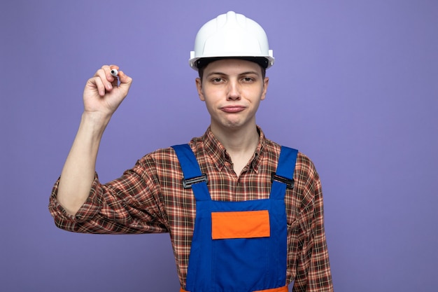 Constructor de sexo masculino joven complacido con marcador de sujeción uniforme