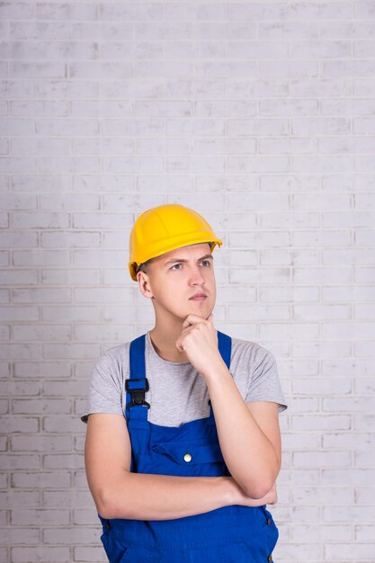 Constructor en uniforme y casco posando sobre pared blanca