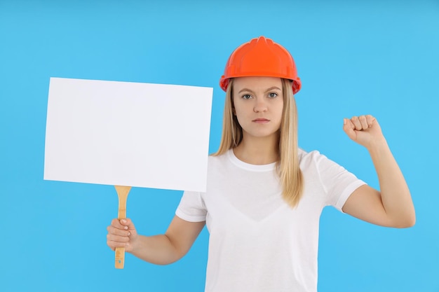 Constructora femenina con signo de protesta vacío sobre fondo azul.