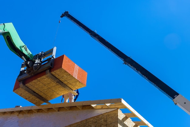 Los constructores están trabajando en el techo cubriéndolo con una capa de madera contrachapada usando hidráulica profesional