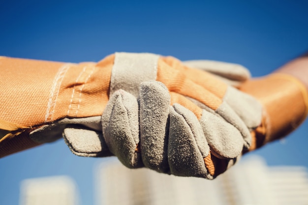 Constructores manos en guantes saludándose