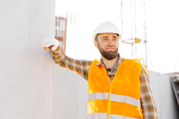 Foto construidor reparador capataz de capacete de segurança e colete trabalha no seu local de trabalho num edifício em construção