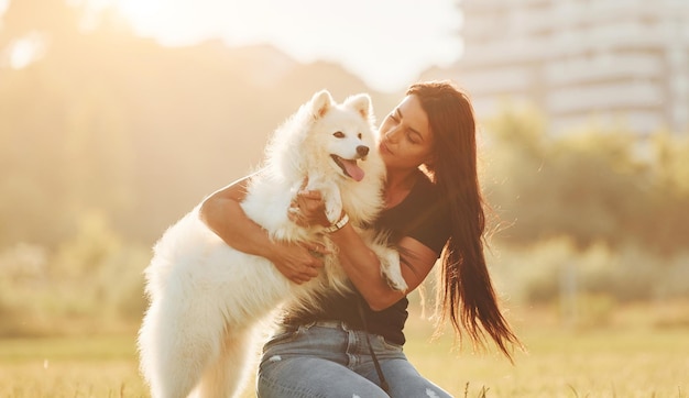 Construindo ao fundo Mulher com seu cachorro está se divertindo no campo em dia ensolarado