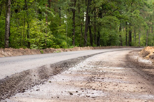 Construindo nova estrada de asfalto no campo. Uma pista está pronta, enquanto a outra precisa de uma camada de acabamento no topo