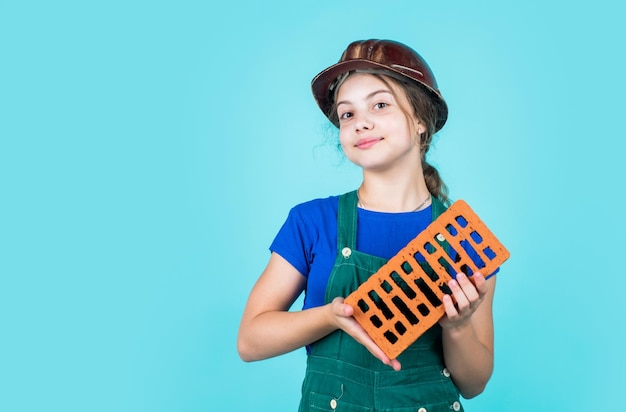 Construindo sua futura casa infância feliz criança use capacete protetor proteja a cabeça no canteiro de obras menina adolescente segura tijolo pequeno construtor com tijolo