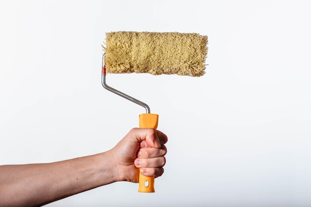 Foto construindo um rolo amarelo para pintar na mão de um homem em um fundo branco