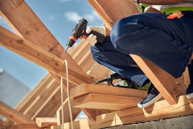 Construtor competente vestindo uniforme e usando instrumento profissional enquanto trabalha na construção
