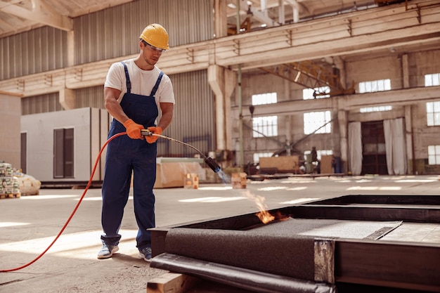 Construtor de homem bonito usando queimador de gás no canteiro de obras