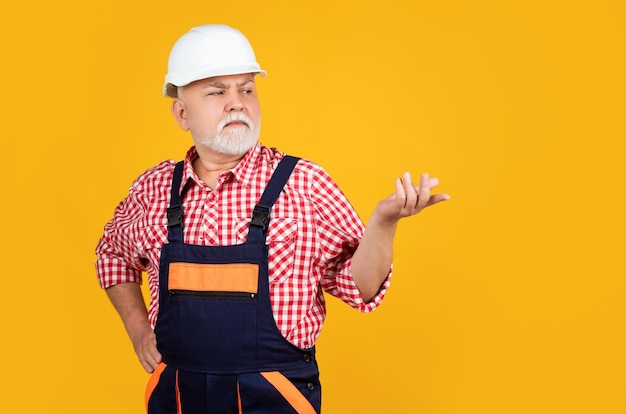 Construtor de homem sênior no capacete em fundo amarelo