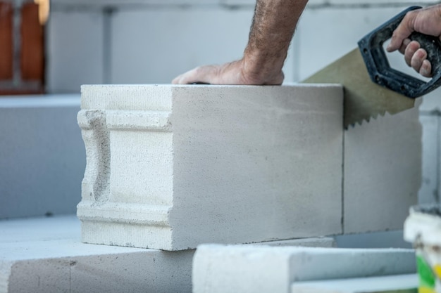 Construtor de homem serrando um tijolo de silicato de gás