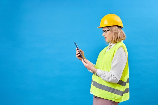 Construtor de mulher de negócios trabalhando com tablet PC Mulher sorridente em estúdio em fundo azul O conceito de decoração de reparo de construção Tiro de estúdio