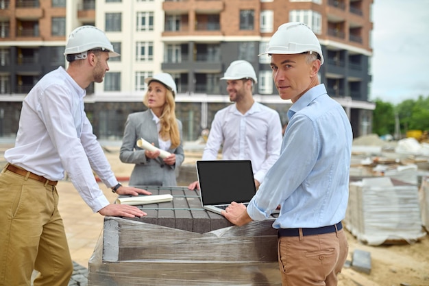 Construtor de pé entre seus três colegas no canteiro de obras