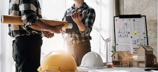 Construtor dois jovem engenheiro asiático e arquiteto estão discutindo a construção de um plano para seguir o projeto para construir uma planta industrial no local Conceito de trabalhador