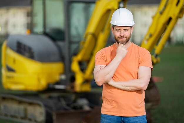 Construtor em um construtor de canteiro de obras com escavadeira pronta para construir um novo construtor de casas