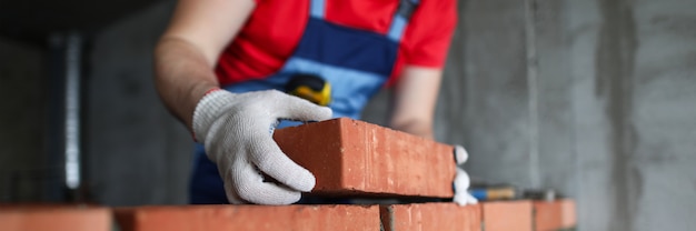 Construtor faz uma parede de tijolos em um close de casa