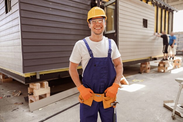 Foto construtor masculino alegre em pé no canteiro de obras