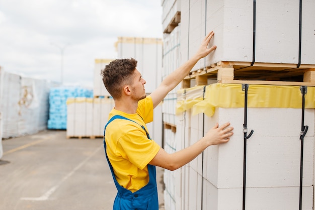 Construtor masculino nas paletes de material de isolamento em loja de ferragens. construtor de uniforme olha as mercadorias na loja de bricolage