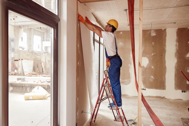 Construtor masculino pendurando papel de parede na parede