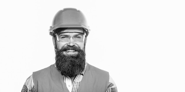 Construtor no capacete, capataz ou reparador no capacete. Retrato de um construtor sorrindo. Trabalhador de homem barbudo com barba na construção de capacete ou capacete. Vidros de construção. Copie o espaço