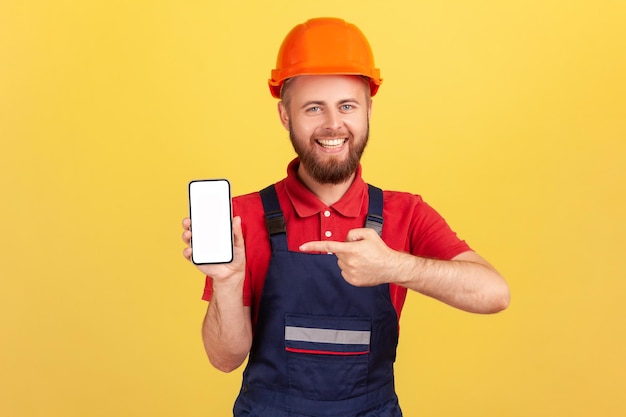 Construtor ou reparador de uniforme e capacete protetor mostrando celular com tela vazia em branco