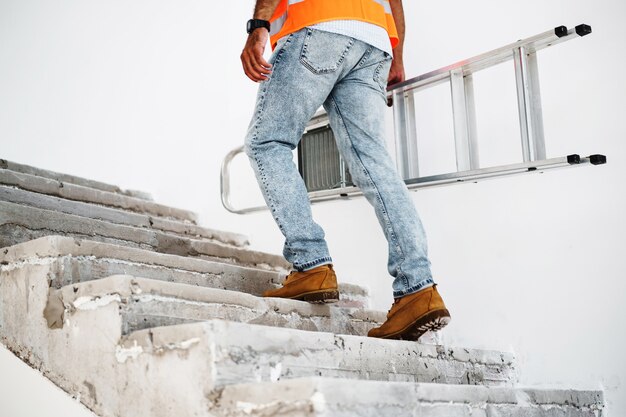 Foto construtor profissional carregando escada de metal de perto