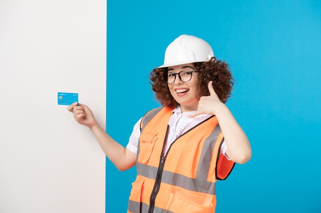 Construtora de frente feminina de uniforme com cartão de crédito azul nas mãos