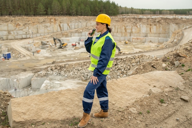 Construtora de uniforme usando walkie-talkie no canteiro de obras