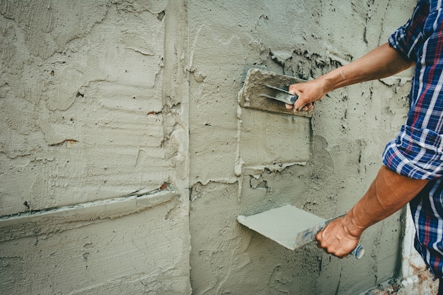 Construtores estão rebocando as paredes da casa com asseio.