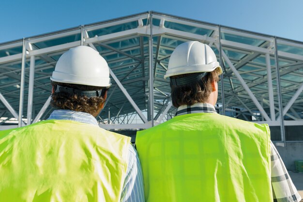 Construtores masculinos no telhado do canteiro de obras, vista traseira