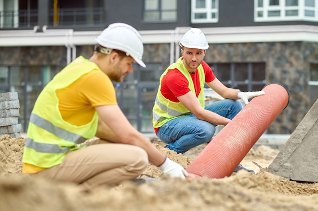 Construtores masculinos qualificados instalando um sistema de drenagem subterrânea