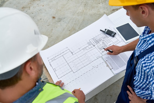 Foto construtores verificando plantas no local