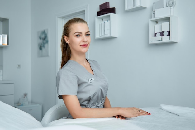 Consulta en la clínica de cosmetología Doctora de belleza en bata blanca y guantes negros con las manos cruzadas