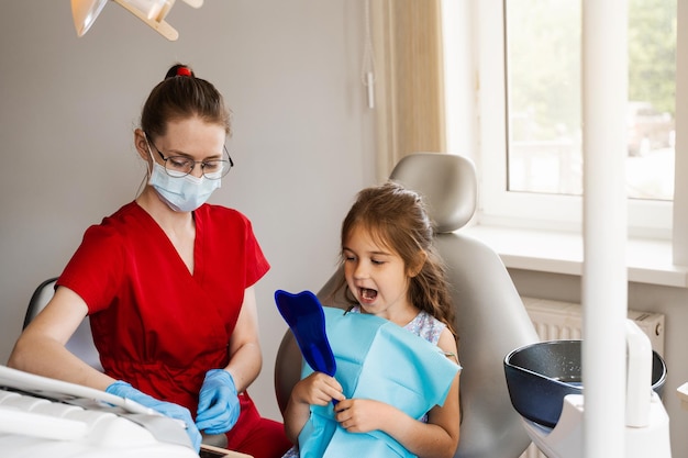 Consulta com dentista infantil na odontologia tratamento dos dentes criança olhando no espelho no dentista paciente criança feliz da odontologia