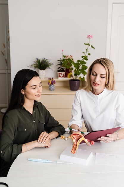 Consulta com ginecologista e discussão sobre saúde reprodutiva da mulher na clínica de ginecologia Ginecologista pergunta à jovem sobre o ciclo menstrual e anota as informações no questionário