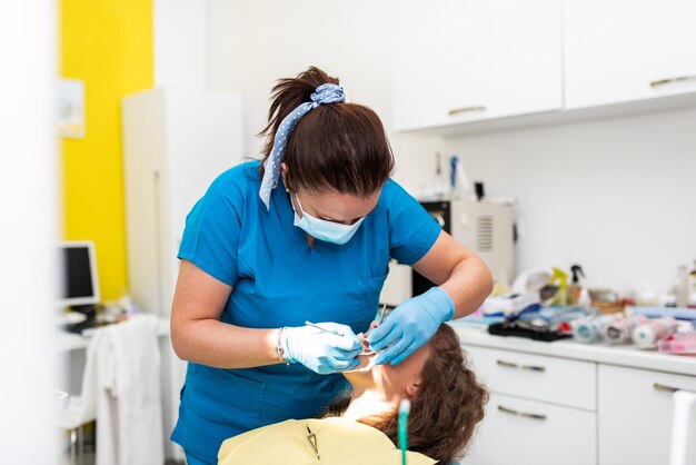 Consulta de dentista em uma clínica odontológica colocando chaves nos dentes e puxando o arco para corrigi-lo