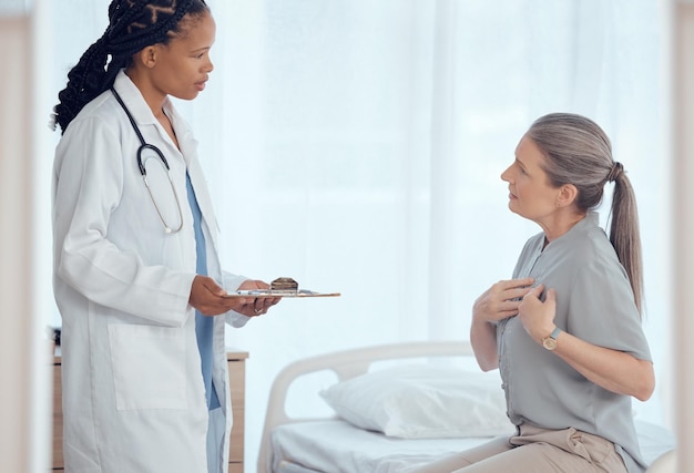 Consulta de saúde e médico com paciente sênior em discussão sobre problema de dor no peito Prancheta profissional e trabalhadora médica conversando com idosa com doença cardíaca no hospital