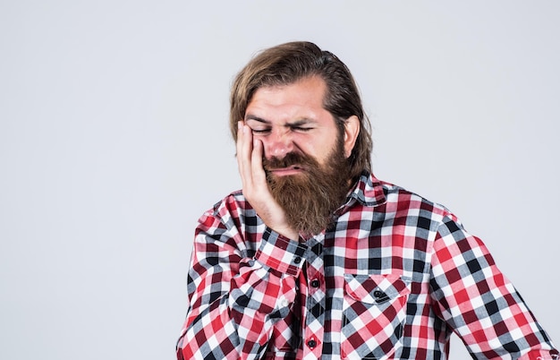 Consulta de dentista Guapo hombre barbudo en ropa casual Sufrimiento Hombre caucásico brutal hipster barbudo tiene dolor de muelas hombre siente dolor en los dientes casual hombre necesita atención médica