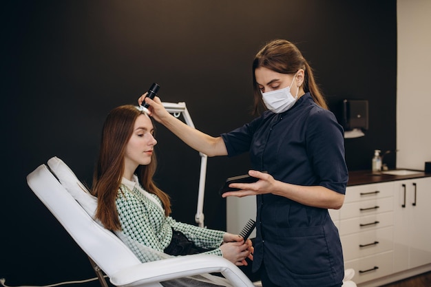 Consulta con un dermatólogo Un tricólogo examina el cabello de una mujer