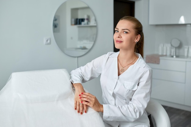 Foto consulta em clínica de cosmetologia médico de beleza feminino com casaco branco e luvas pretas mãos cruzadas