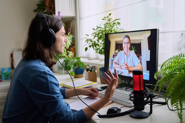 Foto consulta en línea de un estudiante adolescente con auriculares por parte de un trabajador social, psicólogo, profesor de comportamiento, educación, lecciones individuales, webinar, reuniones virtuales, concepto de tecnología moderna.