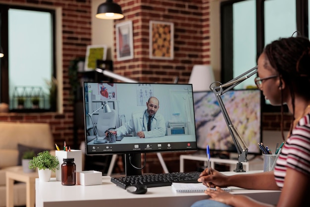 Consulta médica en línea, paciente hablando con el médico, hablando de notas en el cuaderno, discutiendo la salud. Telemedicina, comunicación en vivo con terapeuta en computadora, mujer charlando con médico