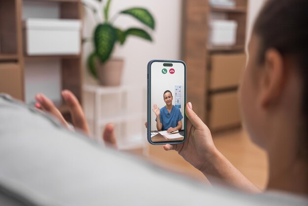 Foto consulta médica virtual con un médico amigable que saluda al paciente a través de un teléfono inteligente