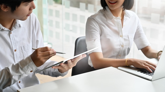 Consulta de negocios jóvenes y reunión sobre mesa de trabajo y tableta digital en las manos.