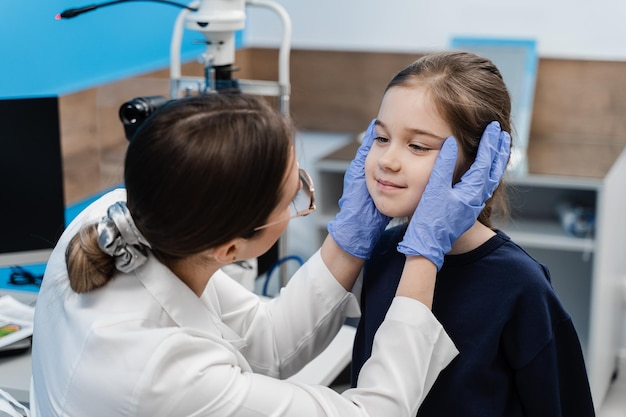 Consulta para niños en la clínica oftalmológica para el tratamiento de la inflamación ocular y la corrección de la visión El oftalmólogo pediátrico examina los ojos y la pupila del niño