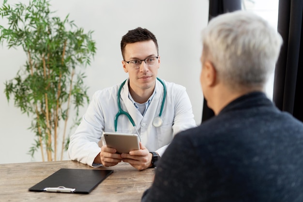 Consulta no médico da clínica com óculos, homem e paciente