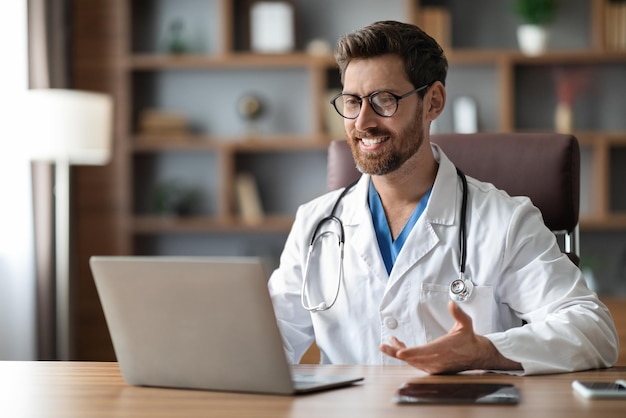 Consulta on-line bonito médico masculino teleconferência com paciente via laptop