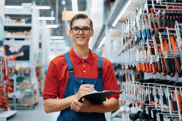 Consultor em uma loja de ferragens fazendo anotações sobre a disponibilidade de produtos nas prateleiras