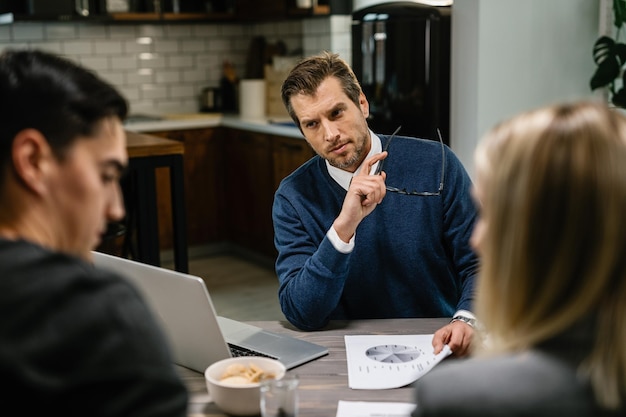 Consultor financeiro se comunicando com um casal sobre seus investimentos futuros durante a reunião