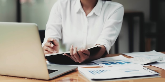 Foto consultor de inversiones empresaria analizando el estado de balance del informe financiero anual de la empresa trabajando con gráficos de documentos.