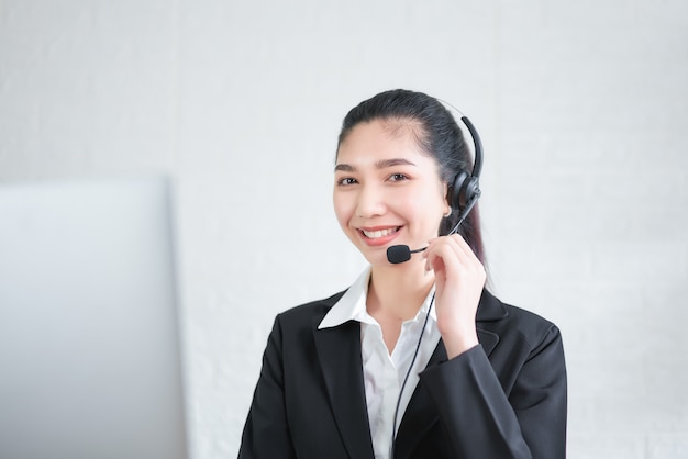 Consultor de mujer asiática sonriente con auriculares de micrófono del operador de teléfono de atención al cliente en el lugar de trabajo.